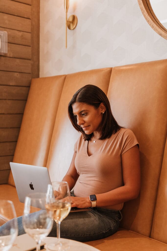 Krystle Straub Travel Agent Marketing Agency. Krystle on her laptop in a winery